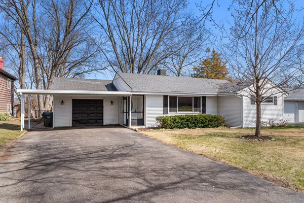a front view of a house with yard and trees in the background