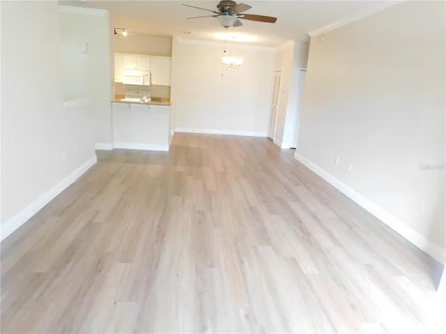 a view of a big room with wooden floor and a kitchen
