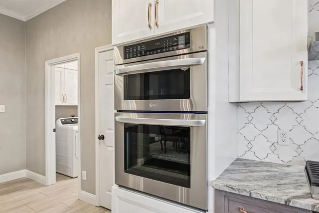 a kitchen with granite countertop white cabinets and stainless steel appliances