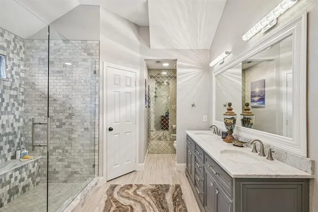 a bathroom with a double vanity sink a large mirror and shower