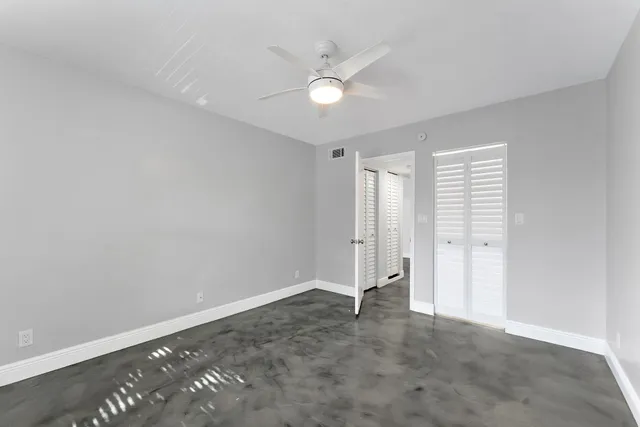an empty room with closet and ceiling fan
