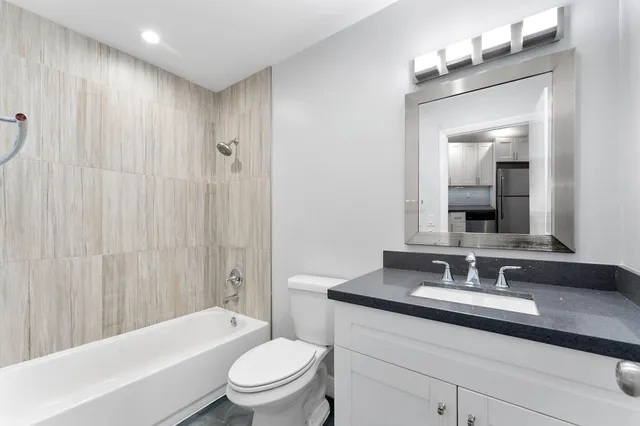 a bathroom with a granite countertop sink a toilet and shower