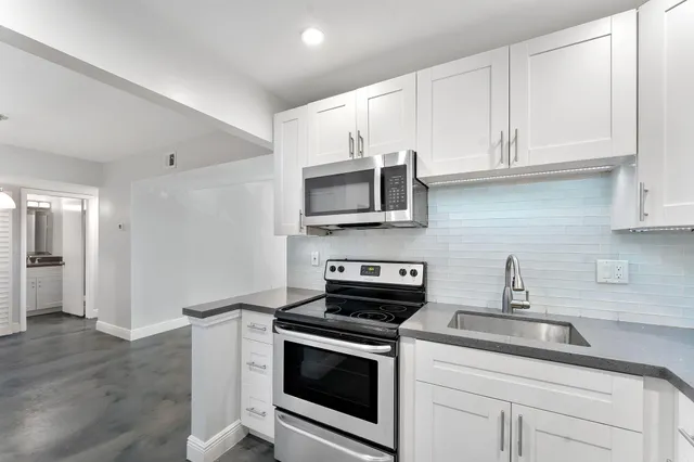 a kitchen with stainless steel appliances granite countertop white cabinets granite counter tops and a hard wood floors