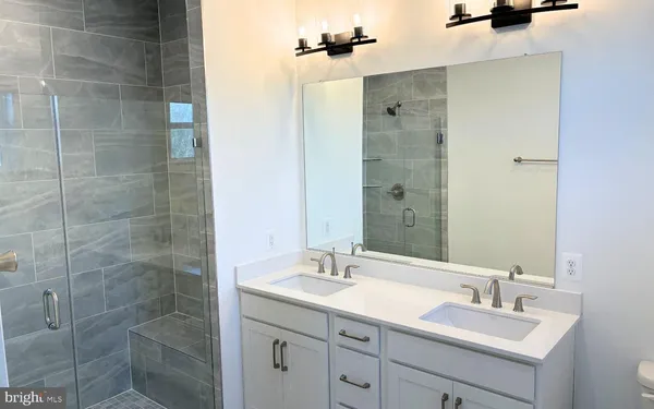 a bathroom with a granite countertop sink a mirror and shower