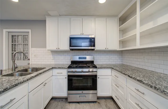a kitchen with granite countertop white cabinets and stainless steel appliances