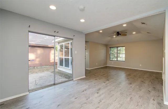 an empty room with wooden floor and windows