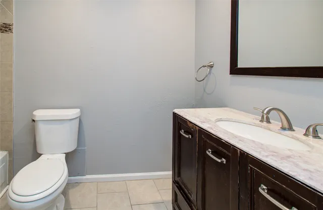 a bathroom with a granite countertop toilet sink and mirror