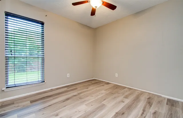 a view of empty room with window and ceiling fan