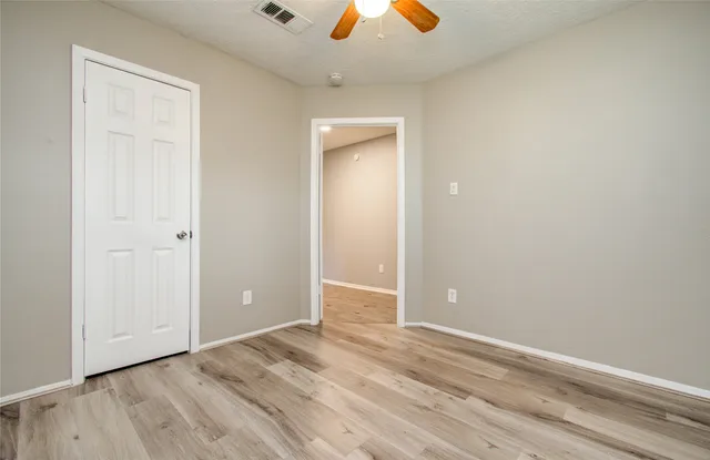 an empty room with closet and a chandelier fan