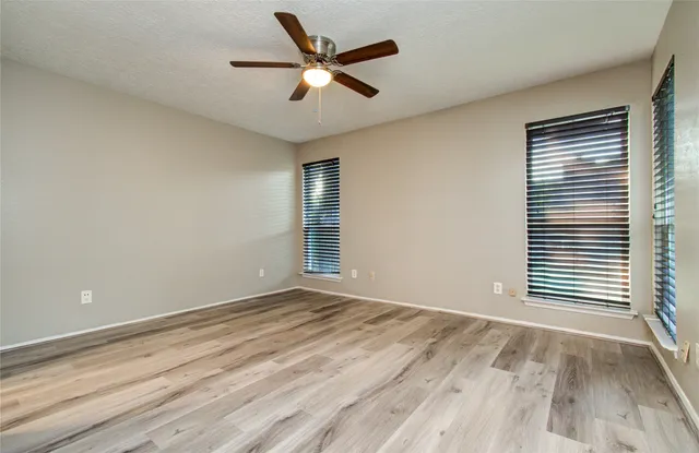 an empty room with wooden floor and windows