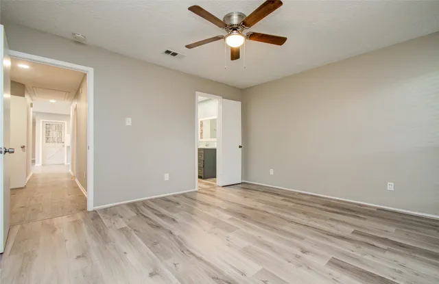 a view of an empty room and window with a chandelier fan