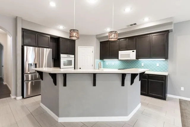 a kitchen with stainless steel appliances kitchen island granite countertop a refrigerator and a sink