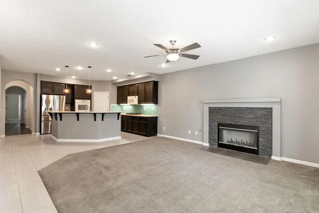 an empty room with chandelier fan and windows