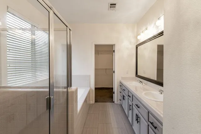 a bathroom with a tub double vanity sink and mirror