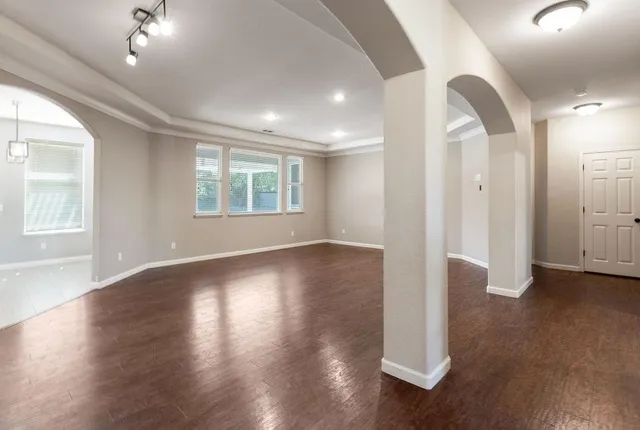 a view of an empty room with wooden floor and a window