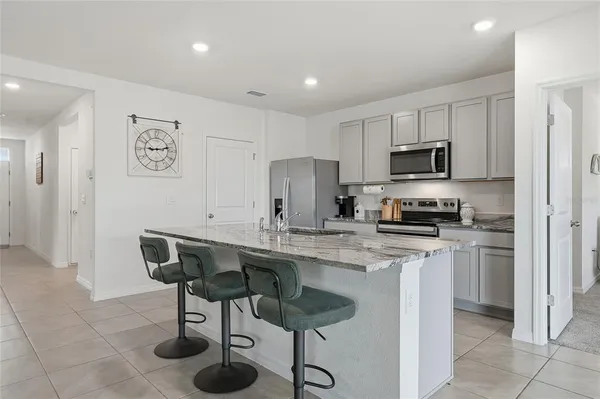 a kitchen with stainless steel appliances granite countertop a sink a stove a refrigerator a microwave oven with white cabinets and wooden floor