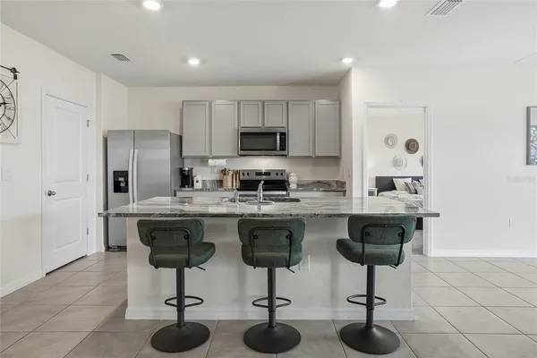 a kitchen with stainless steel appliances granite countertop a sink a stove a refrigerator a counter space and chairs