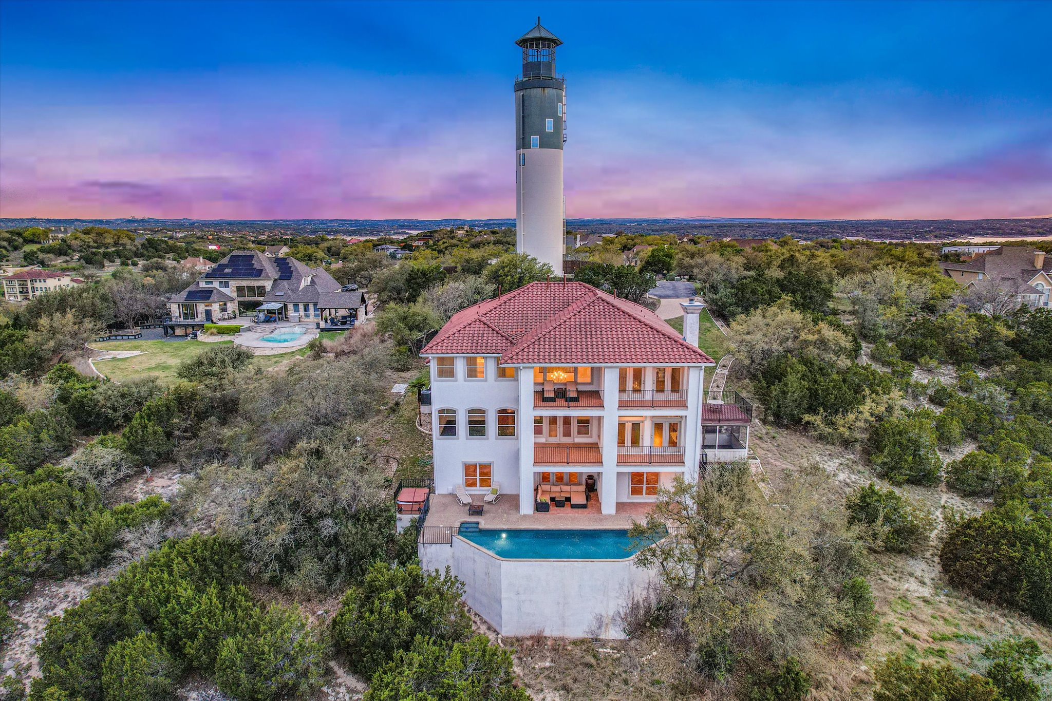 4319 Rum Runner Road Austin, TX 78734 - Photo 3 of 40 Back of property at dusk featuring a chimney, an outdoor pool, a patio, a balcony, and view of wooded area