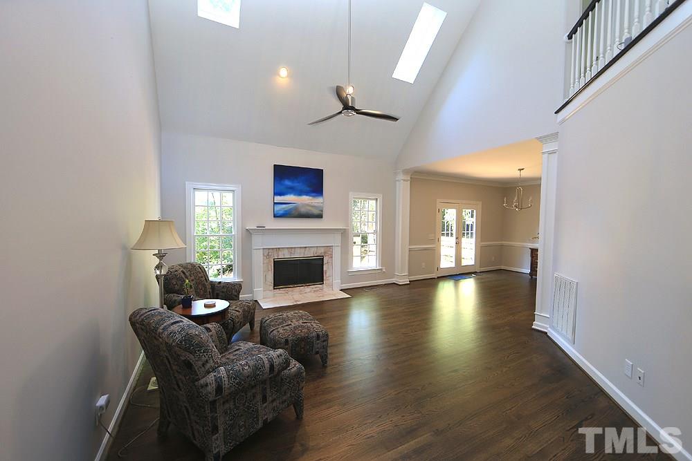 1901 Russell Drive Raleigh, NC 27612 - Photo 3 of 18 Spacious Family Room with vaulted ceiling, skylights, ceiling fan, fireplace with mantle & surround and refinished hardwood floors.