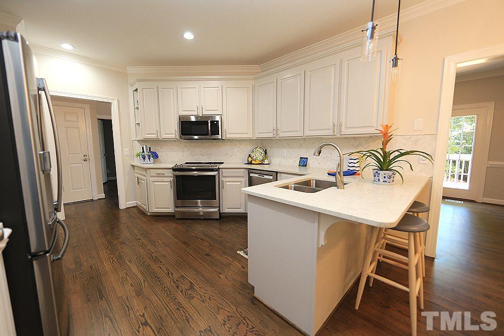 1901 Russell Drive Raleigh, NC 27612 - Photo 6 of 18 Beautifully updated kitchen with white cabinets, Quartz countertops, tile backsplash, SS GE Range/Oven, Spacemaker Microwave, Bosch Dishwasher, Refrigerator, breakfast bar, direct & pendant lighting, 2 pantrys and refinished hardwood floors.