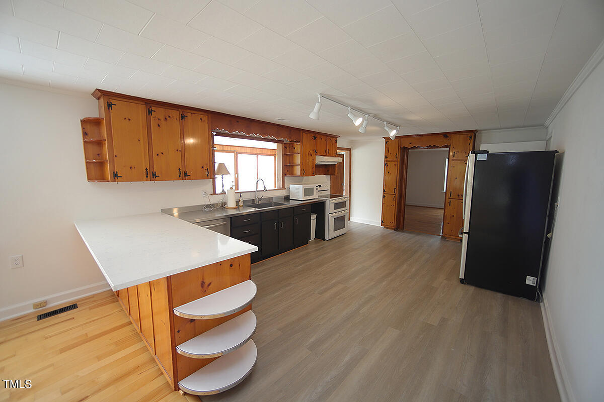 305 West Watson Road Benson, NC 27504 - Photo 7 of 30 a kitchen with stainless steel appliances granite countertop a refrigerator a stove and a wooden floors