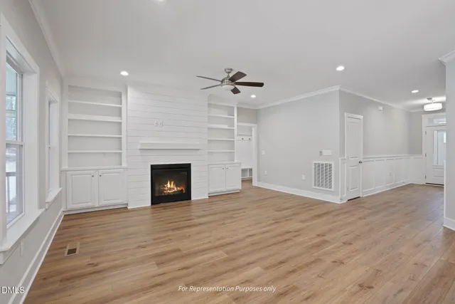 a view of a livingroom with a fireplace a ceiling fan and window