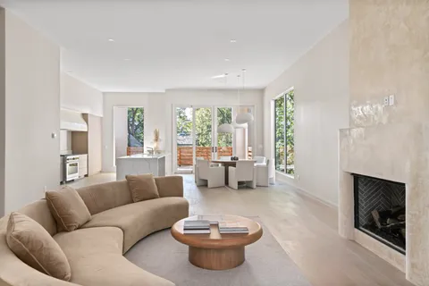 a kitchen with a stove a refrigerator and a view of living room