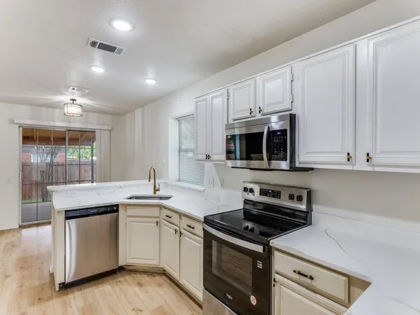 a kitchen with stainless steel appliances granite countertop a stove a sink and a microwave