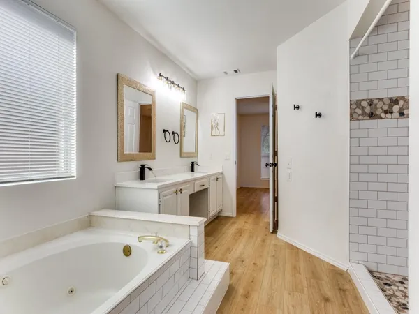 a bathroom with a tub a sink and a mirror