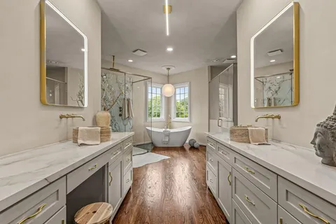 a spacious bathroom with double vanity a large mirror a vanity and a shower