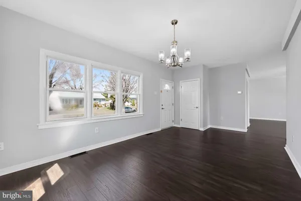 a view of empty room with wooden floor and window