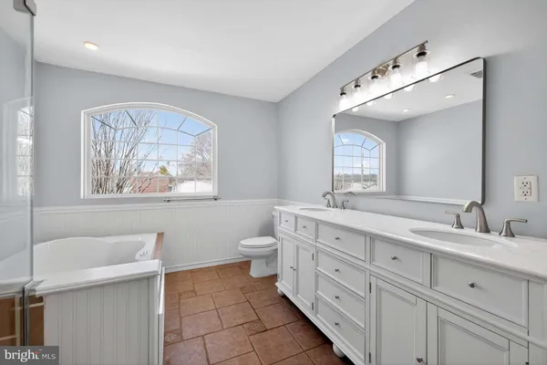 a spacious bathroom with a double vanity sink mirror and bathtub