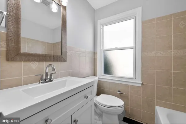 a bathroom with a sink toilet a mirror and a window