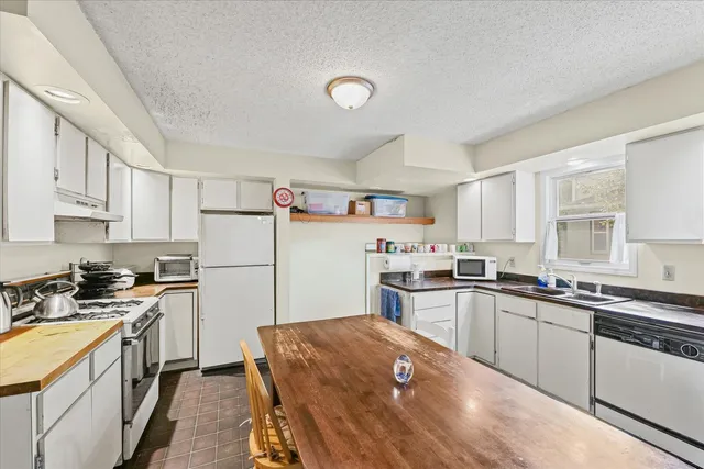 a kitchen with a sink a stove a refrigerator and white cabinets