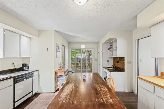 a kitchen with granite countertop a stove a sink a refrigerator and white cabinets with wooden floor