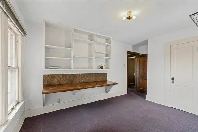 a view of an empty room with cabinet and a window