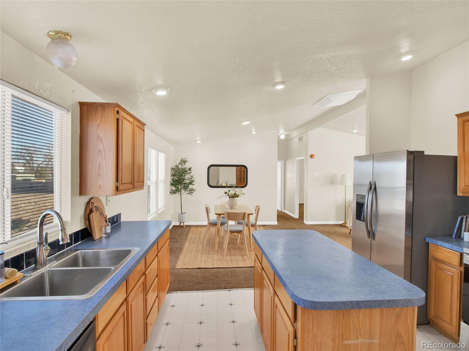 7798 Richard Avenue Fort Lupton, CO 80621 - Photo 12 of 45 a kitchen with stainless steel appliances granite countertop a sink dishwasher a refrigerator and a dining table with wooden cabinet