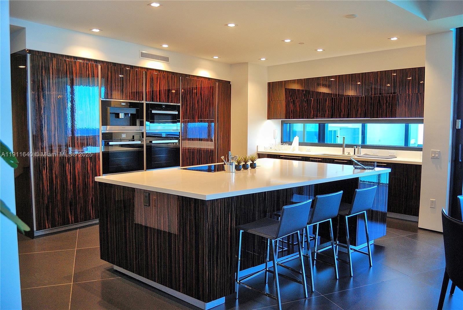 18555 Collins Avenue, Unit 3005 Sunny Isles Beach, FL 33160 - Photo 12 of 57 a kitchen with stainless steel appliances kitchen island granite countertop a table chairs and a refrigerator