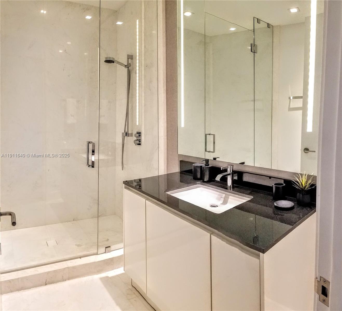 18555 Collins Avenue, Unit 3005 Sunny Isles Beach, FL 33160 - Photo 37 of 57 a bathroom with a granite countertop sink a mirror and a shower