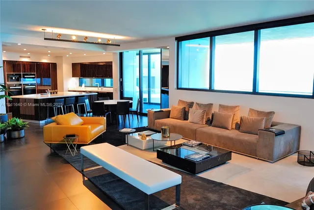 a living room with stainless steel appliances kitchen island granite countertop a refrigerator a sink dishwasher a dining table and chairs with wooden floor