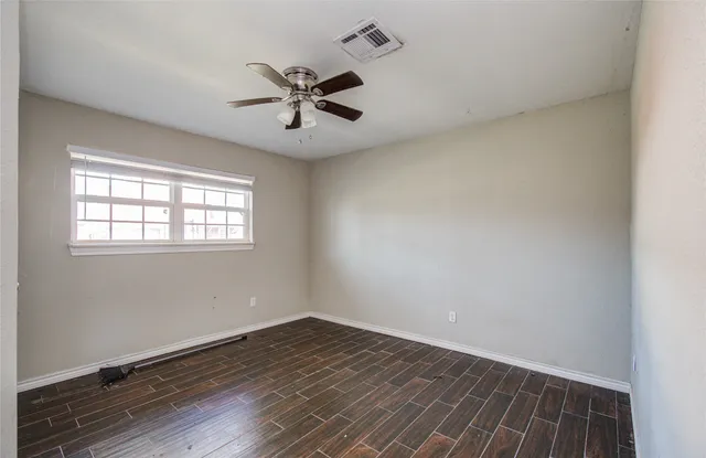 a view of a livingroom with a hardwood floor a ceiling fan and window