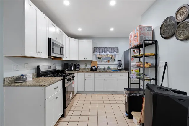 a kitchen with stainless steel appliances granite countertop a stove a sink and dishwasher with white cabinets
