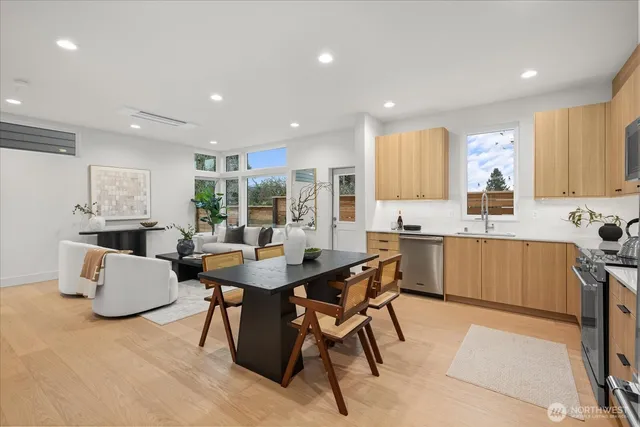 a kitchen with stainless steel appliances kitchen island granite countertop a sink a stove a dining table and chairs