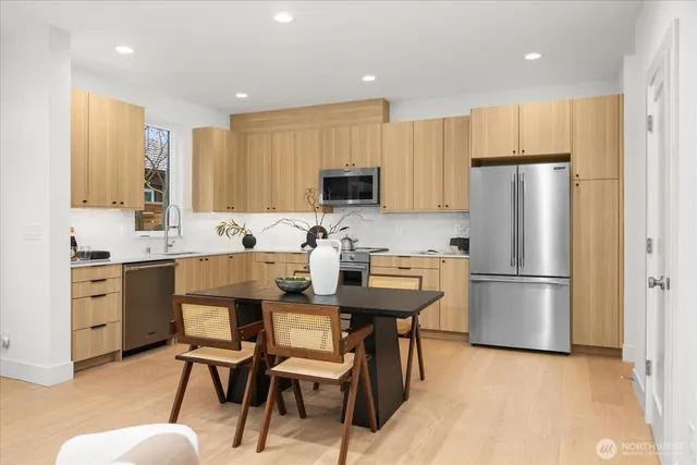 a kitchen with a refrigerator a stove a microwave oven with a dining table and chairs