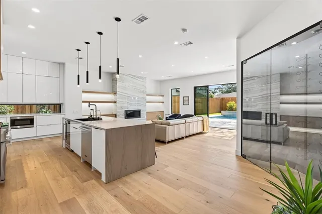 a large kitchen with stainless steel appliances a large counter top a stove a sink and a refrigerator