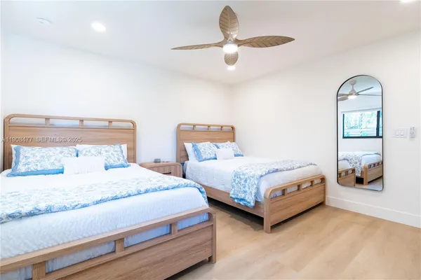 a bedroom with two beds and ceiling fan