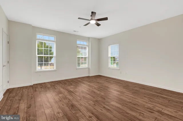 a view of empty room with wooden floor and fan