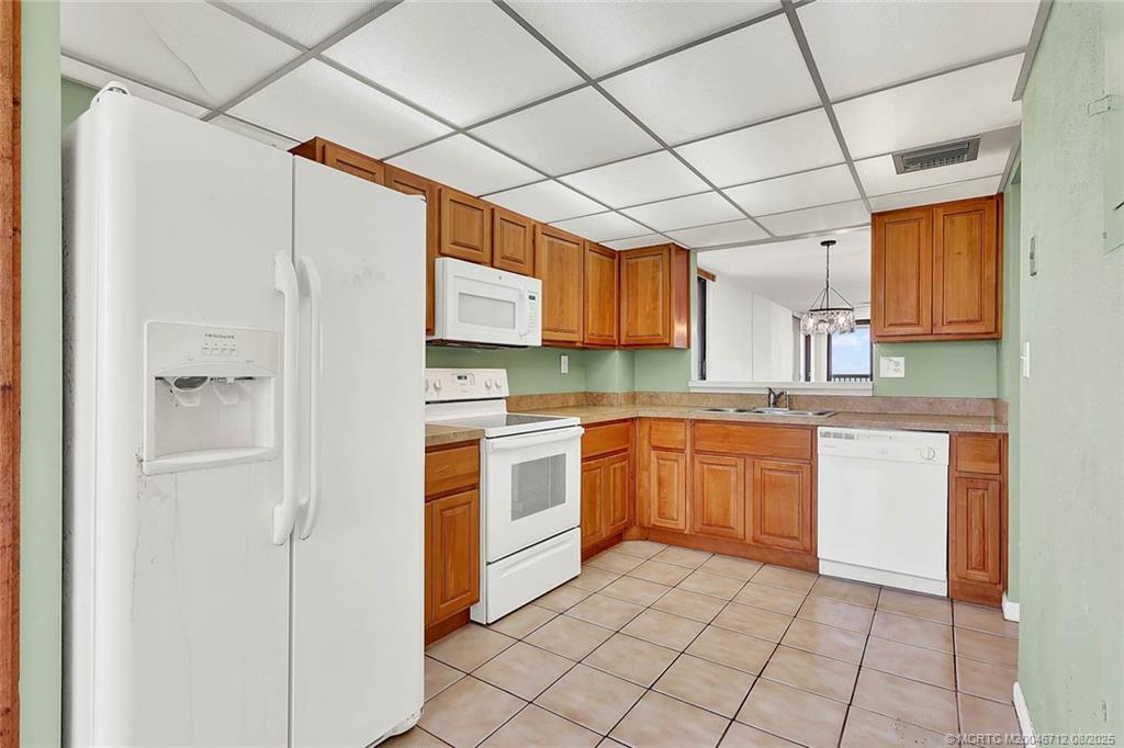 10600 South Ocean Drive, Unit 201 Jensen Beach, FL 34957 - Photo 12 of 40 a kitchen with stainless steel appliances granite countertop a refrigerator and a stove top oven