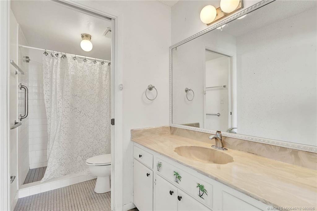10600 South Ocean Drive, Unit 201 Jensen Beach, FL 34957 - Photo 26 of 40 a bathroom with a granite countertop sink a toilet and a shower