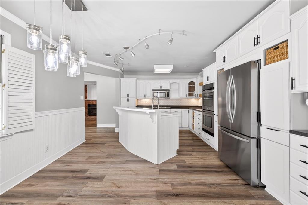 627 Rock Springs Road Lawrenceville, GA 30043 - Photo 12 of 85 a large white kitchen with wooden floor and a refrigerator